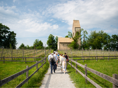 Eine Gruppe unterwegs auf der Insel Ufnau mit Kirche im Hintergrund.